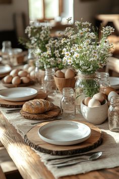 the table is set with eggs, bread and flowers in vases on top of it