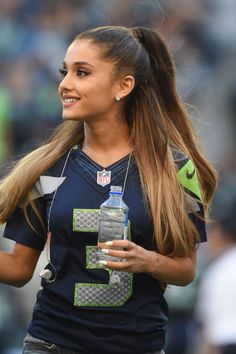 a female football player holding a water bottle in her right hand and wearing a ponytail