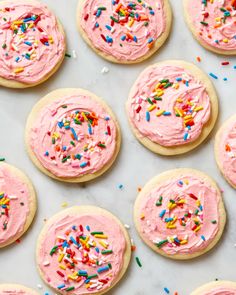 cookies with pink frosting and sprinkles on a table