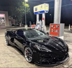 a black sports car parked in front of a gas station