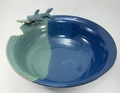 a blue and green bowl with a small animal on the side in front of it