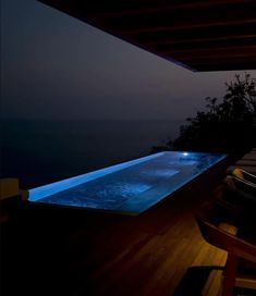 an outdoor swimming pool at night with the lights on and water running down it's sides