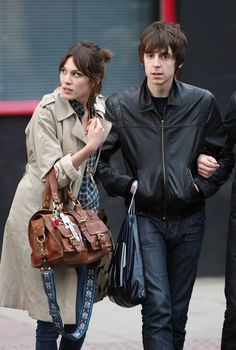 two people are walking down the street with handbags in their hands and one is carrying a purse