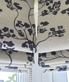 two curtains with black flowers on them in front of a window