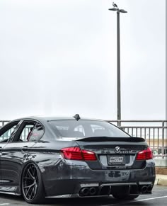 a grey bmw parked in a parking lot next to a fence and street light with the word