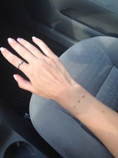 a woman's hand in the back seat of a car with three small dots on her left wrist