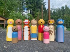 a group of wooden toy figures standing next to each other on the ground with trees in the background