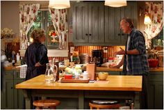 two people standing in a kitchen next to an island