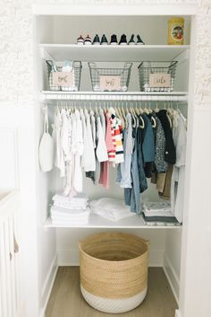 an organized closet with clothes and baskets on the shelves, along with baby's clothing