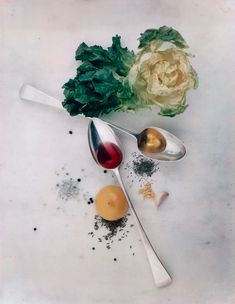 an assortment of spices and spoons on a white surface with a flower in the background