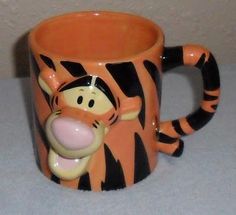 a winnie the pooh coffee mug with an orange and black tiger design on it
