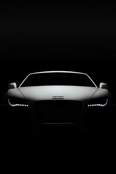 a white car in the dark with its headlights turned on and it's headlight up