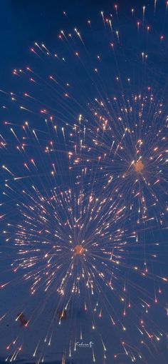 fireworks are lit up in the night sky with blue skies and white clouds behind them