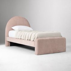 a bed with a pink headboard and foot board on it's side, in front of a gray wall