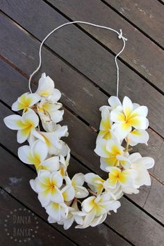 a white and yellow flower wreath on a wooden floor with string hanging from it's center