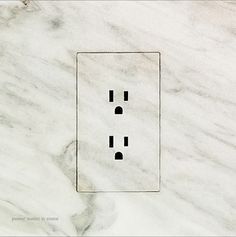 an electrical outlet cover with two black dots on it's white marble wallpaper