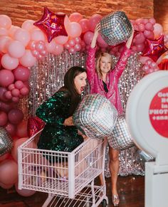 two women standing in front of balloons and disco balls