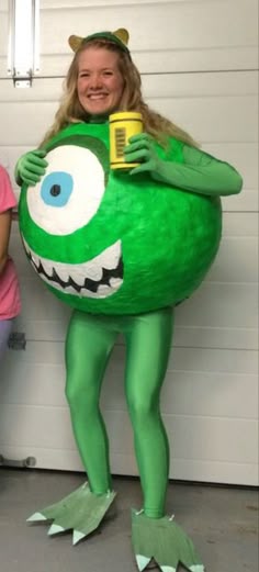 two girls in costumes standing next to each other with a large green monster costume on
