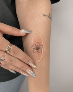 a woman's arm with a flower tattoo on the left side of her arm