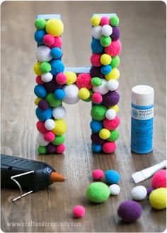 the letter h made out of pom - poms is next to some crafting supplies