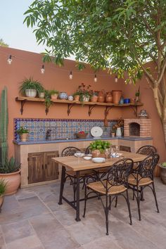 an outdoor dining area with potted plants and pots on the wall, table set for four