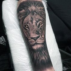 a black and grey lion tattoo on the arm