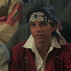 a young man wearing a bandana and headband in front of an american flag