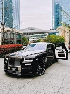 a black and white rolls royce parked in front of tall buildings
