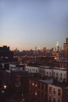 the city skyline is lit up at night, with buildings in the foreground and skyscrapers in the background
