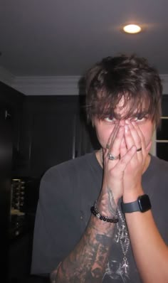 a young man covers his face with both hands