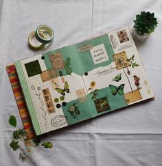 an open book on a table next to some flowers and other things that are sitting on top of it