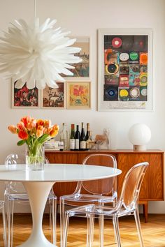 a dining room table with chairs and a vase filled with flowers on top of it