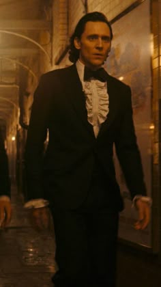 a man in a tuxedo is walking down the street