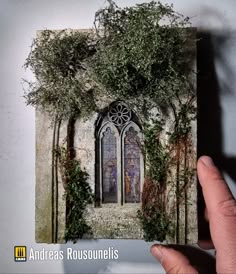 a hand holding up a card with an image of a window and vines on it