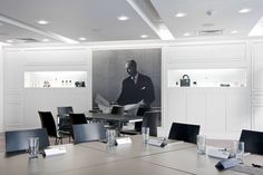 an empty conference room with black and white pictures on the wall, chairs and tables