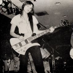a woman sitting on top of a chair while holding a guitar in front of her