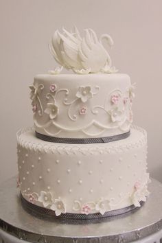 a three tiered cake with white frosting and pink flowers on the bottom layer