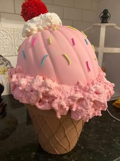 an ice cream cone with pink frosting and sprinkles