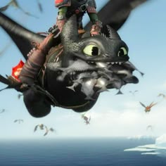 a man riding on the back of a black dragon flying through the air over water