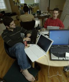 two men sitting at a table with laptops