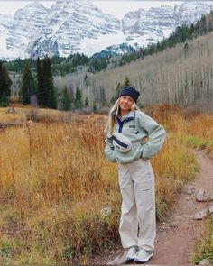 a woman standing on a dirt path in the mountains