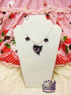 a necklace with bats hanging from it on a mannequin headdress background