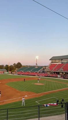 a baseball game is being played on a sunny day in the stadium with red bleachers