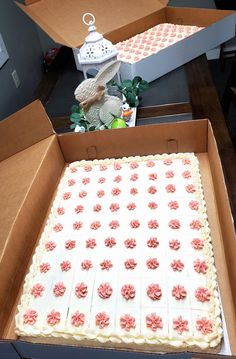 a cake in a box with pink flowers on it and an animal figurine next to it