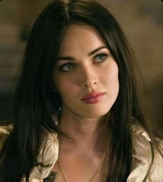 a close up of a person with long hair and blue eyes wearing a gold necklace