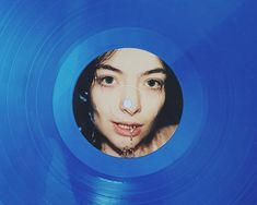 a woman's face is seen through the hole in a blue vinyl album cover