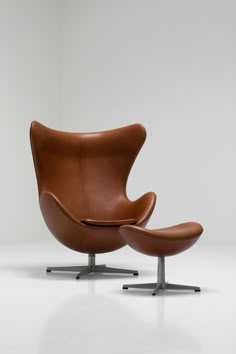 an egg chair and ottoman in brown leather