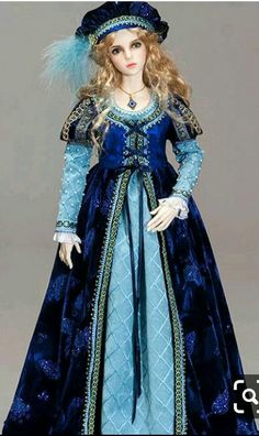 a doll wearing a blue dress and hat with feathers on it's head is standing in front of a gray background