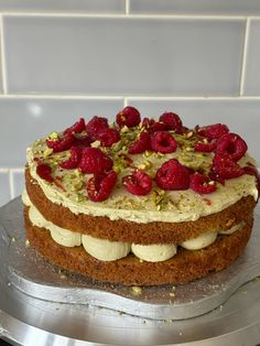a cake that is sitting on top of a plate with raspberries and pistachios