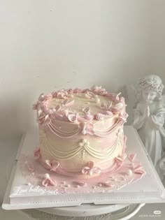 a pink cake sitting on top of a white plate next to a figurine
